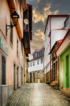 Calle estrecha de Chaves con casas tradicionales, balcones y cielo azul al fondo.