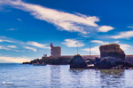 Paisaje costero de Lagos con fortificación, cielo azul y aguas del Algarve.