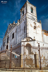 Iglesia histórica de Lagos, Portugal, fotografiada desde abajo con fachada blanca y cielo azul intenso.