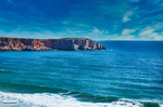 Acantilados rojizos del Algarve junto al mar azul cerca de Lagos, Portugal.