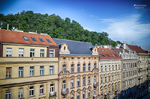 Fachadas clásicas junto al río en Praga con tejados rojos y cielo azul.