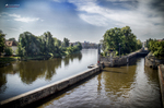 Canal o ribera del Moldava en Praga con árboles y reflejos en el agua.