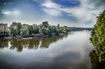 Paisaje del río Moldava en Praga con árboles reflejados y cielo abierto.