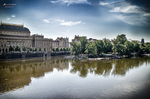 Edificio histórico junto al río Moldava en Praga con reflejos sobre el agua.