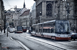 Tranvía circulando por una calle antigua de Praga junto a una iglesia gótica.