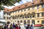 Patio interior con arcadas, tejados rojos y visitantes en el centro histórico de Praga.