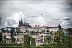Vista panorámica de Praga con torres y tejados bajo un cielo nublado.