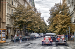Calle de Praga con coches clásicos rojos y árboles de otoño.