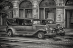 Coche antiguo en blanco y negro delante de una fachada histórica de Praga.