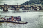 Vista del Puente de Carlos y el río Moldava con embarcaciones turísticas en Praga.