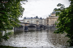 Puente sobre el río Moldava en Praga visto entre árboles y arquitectura clásica.