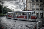 Tranvía rojo y blanco circulando por una calle empedrada de Praga.
