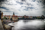 Vista del río Moldava en Praga con puentes, tejados y cielo nublado.