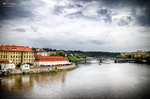 Vista del río Moldava en Praga con edificios históricos y cielo gris.