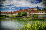 Palacio y jardines junto al río Moldava en Praga con cielo azul y nubes.