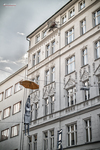 Fachada de Praga con rótulos colgantes y arquitectura clásica.