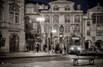 Plaza nocturna de Praga con edificios iluminados y ambiente urbano.