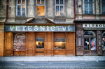 Fachada de tienda de antigüedades en Praga con letrero iluminado y escaparates.