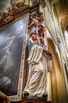 Estatua religiosa iluminada junto a una pintura barroca en Kutná Hora.