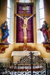 Altar con crucifijo y cortinaje rojo en una iglesia de Kutná Hora.