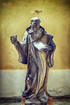 Escultura de santo con túnica y cruz en un interior religioso de Kutná Hora.