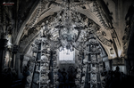 Interior oscuro del Osario de Sedlec con arcos y decoración de huesos humanos.