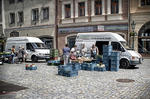 Mercado callejero en una plaza de Kutná Hora con puestos, furgoneta y edificios históricos.