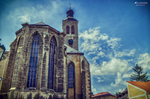 Iglesia gótica de Kutná Hora con grandes ventanales y cielo azul dramático.
