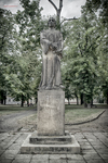 Estatua conmemorativa en el Memorial de Terezín, República Checa, rodeada de árboles.