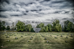 Campo conmemorativo de Terezín con paisaje abierto y cielo dramático.