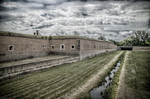 Murallas y foso de la Pequeña Fortaleza de Terezín bajo un cielo gris.