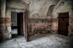Habitación deteriorada de Terezín con puertas abiertas y paredes desgastadas.