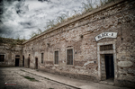 Fachada de barracón en Terezín con puerta señalizada y cielo nublado.