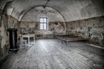 Sala abovedada de Terezín con mesa, estufa y paredes envejecidas.