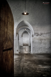 Pasillo abovedado de Terezín con puerta abierta y luz al fondo.