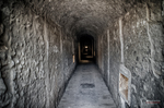Túnel estrecho de piedra o ladrillo en el Memorial de Terezín con luz al fondo.