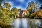 Canal o lago de Brujas con casas históricas, árboles y reflejos bajo cielo azul.