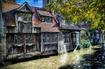 Fachadas antiguas de madera y ladrillo reflejadas en un canal de Brujas.