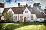 Casa blanca con puerta roja y jardín en una zona histórica de Brujas.