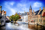 Canal de Brujas con barcas, casas históricas y torre de iglesia al fondo.