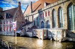 Edificio histórico de ladrillo junto al canal de Brujas con luz de tarde.