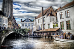 Puente sobre un canal de Brujas con casas antiguas y ambiente turístico.
