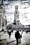 Fotografía en blanco y negro del campanario de Brujas con personas en la plaza.