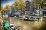 Bicicleta junto a un canal de Ámsterdam con casas históricas y árboles de otoño.