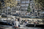 Casas históricas de Ámsterdam frente al canal con barcas y atmósfera urbana tranquila.
