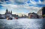 Vista amplia de Ámsterdam desde el agua con barcos, edificios históricos y cielo azul.