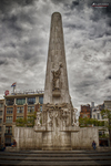 Monumento Nacional de Ámsterdam en la Plaza Dam bajo un cielo dramático de nubes.