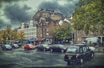 Calle urbana de Escocia con coches aparcados, árboles de otoño y edificios históricos.