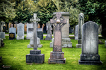 Lápidas antiguas en un cementerio de Escocia rodeado de árboles.