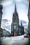 Monumento gótico de Edimburgo elevándose sobre una calle bajo cielo azul.